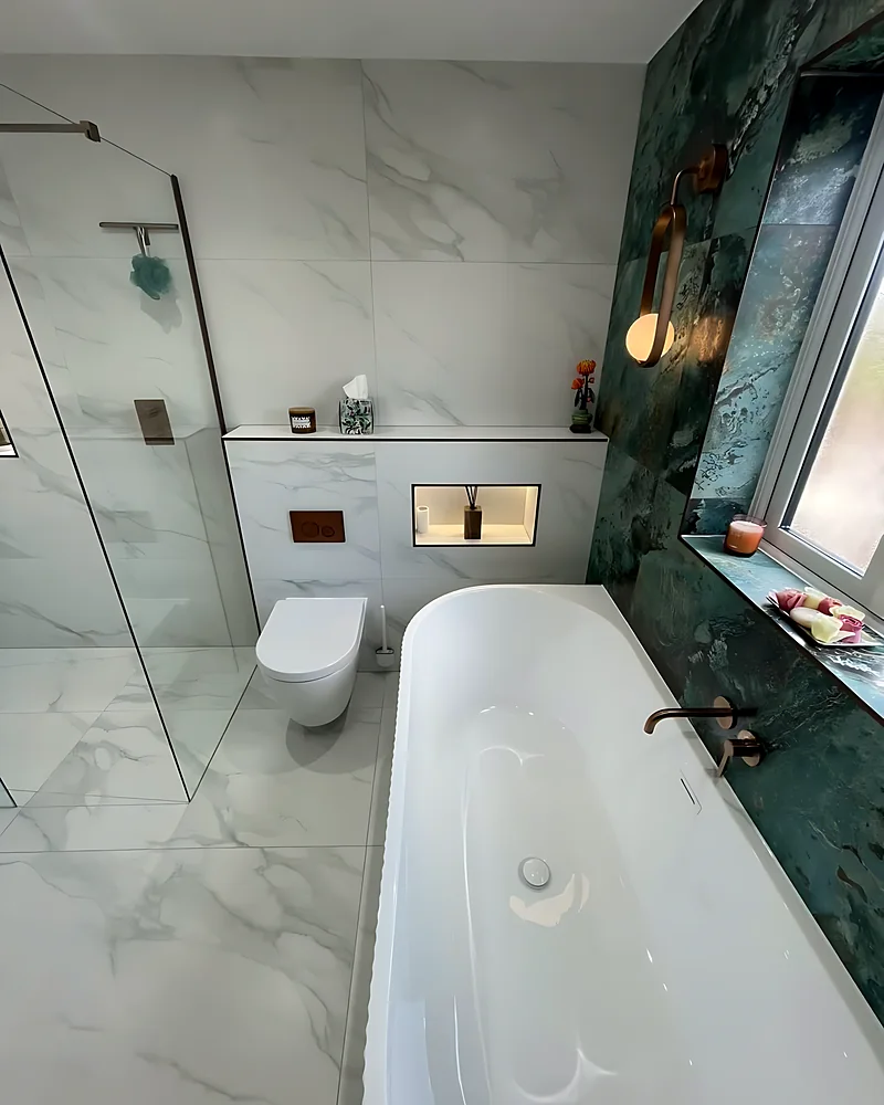 Freestanding bath beside the green marble-effect wall and the shower screen