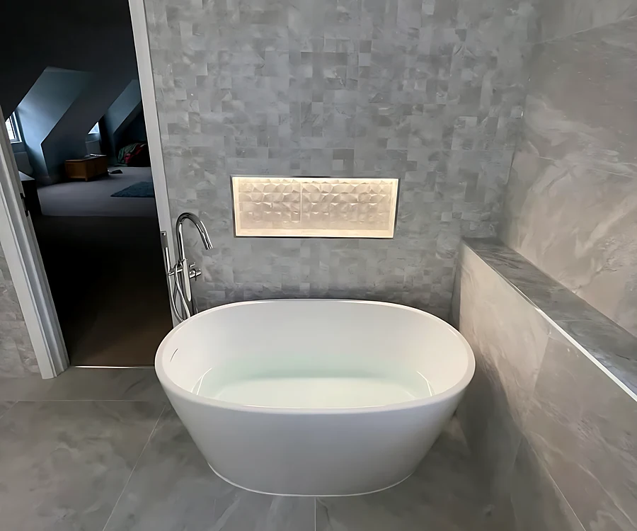 Hutton en suite with a freestanding bath and a lit niche in a stone-effect wall