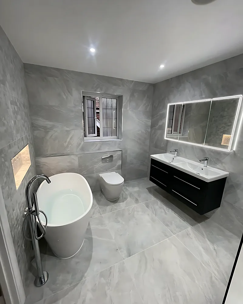 Freestanding bath and a dark vanity with a long LED mirror