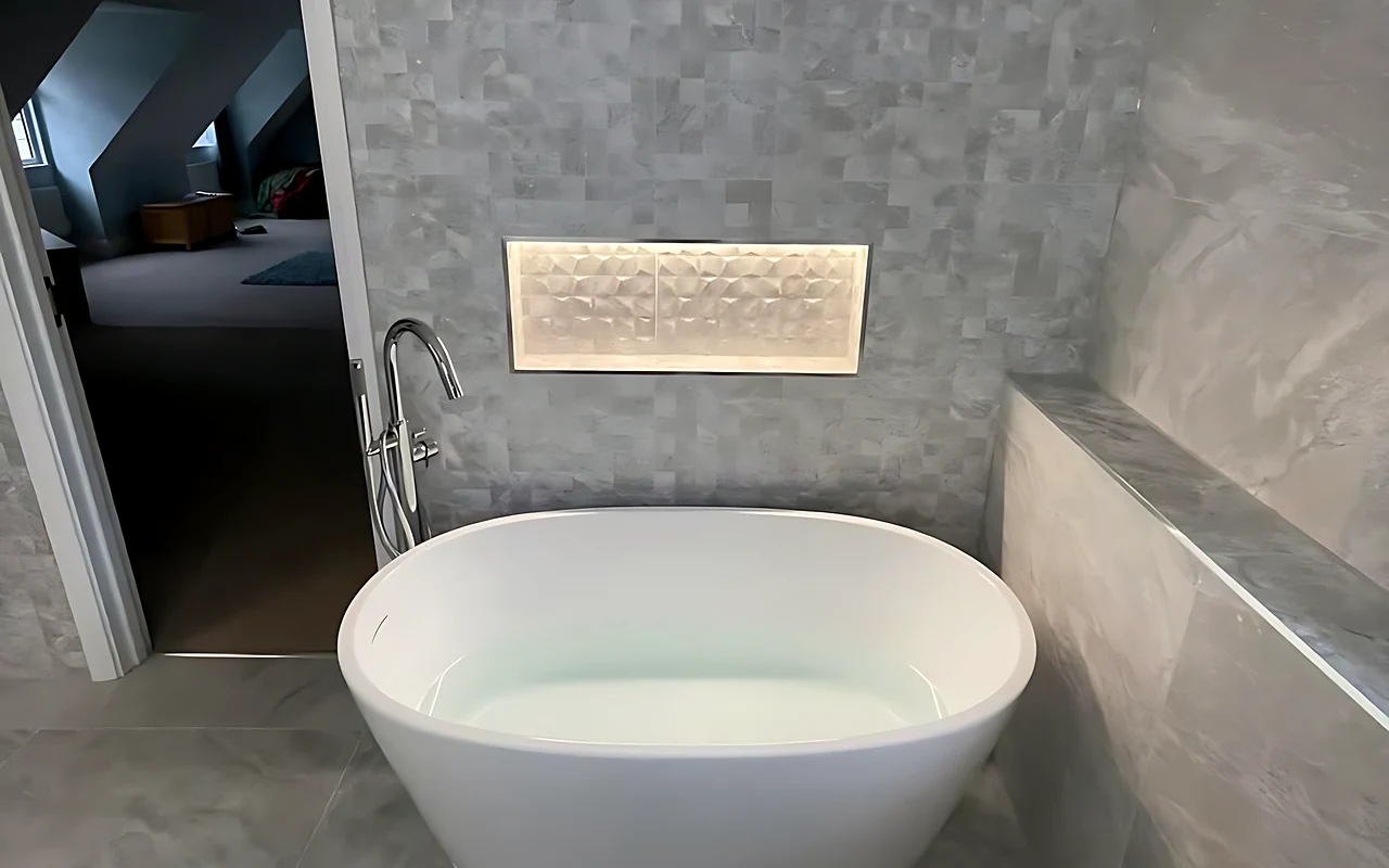 Hutton en suite with a freestanding bath and a lit niche in a stone-effect wall