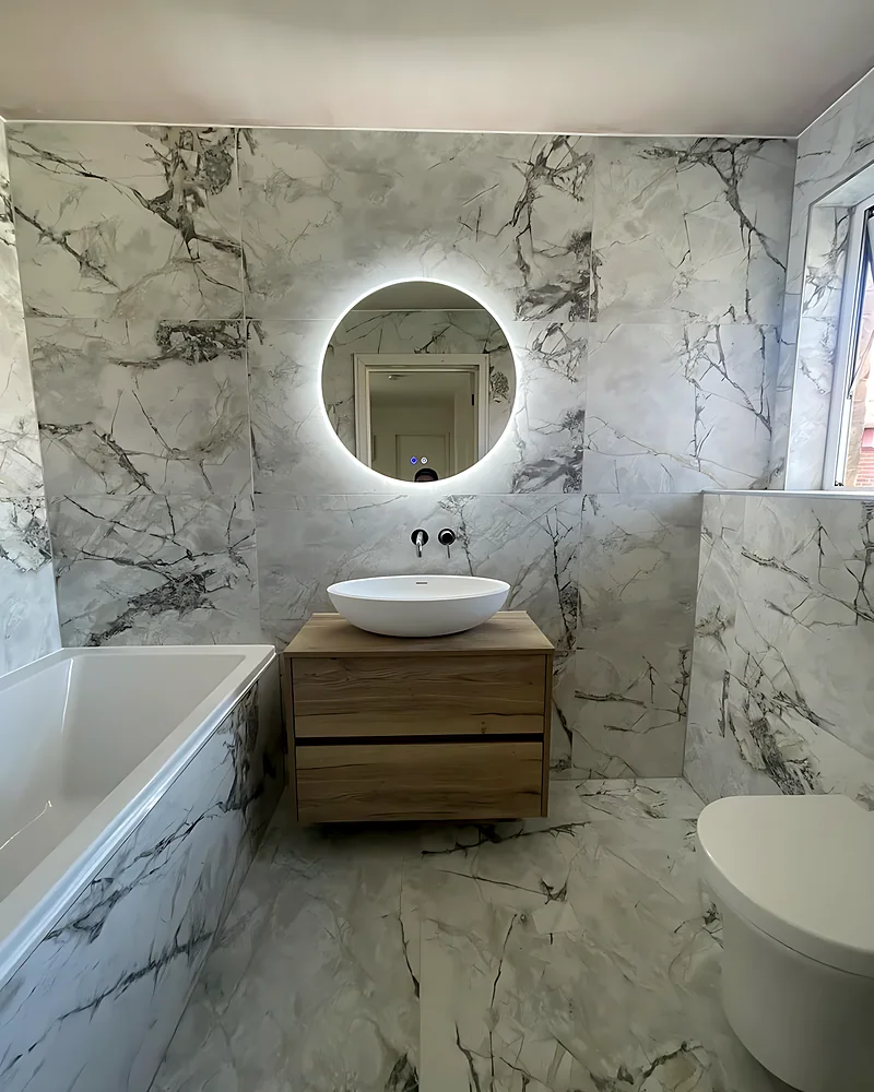 Wood vanity with a countertop basin under a round LED mirror