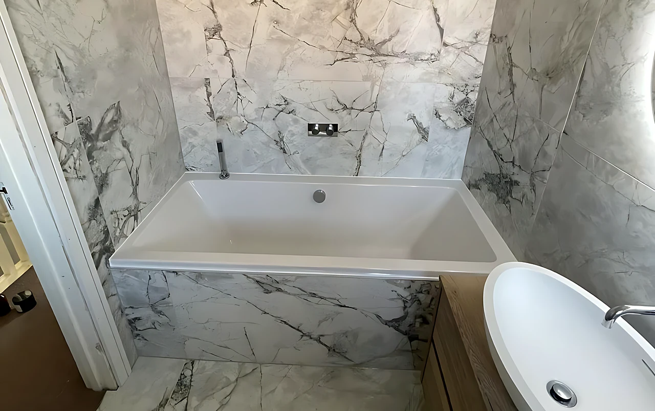 South Woodham Ferrers bathroom with a bath set into marble-effect porcelain on the walls and floor